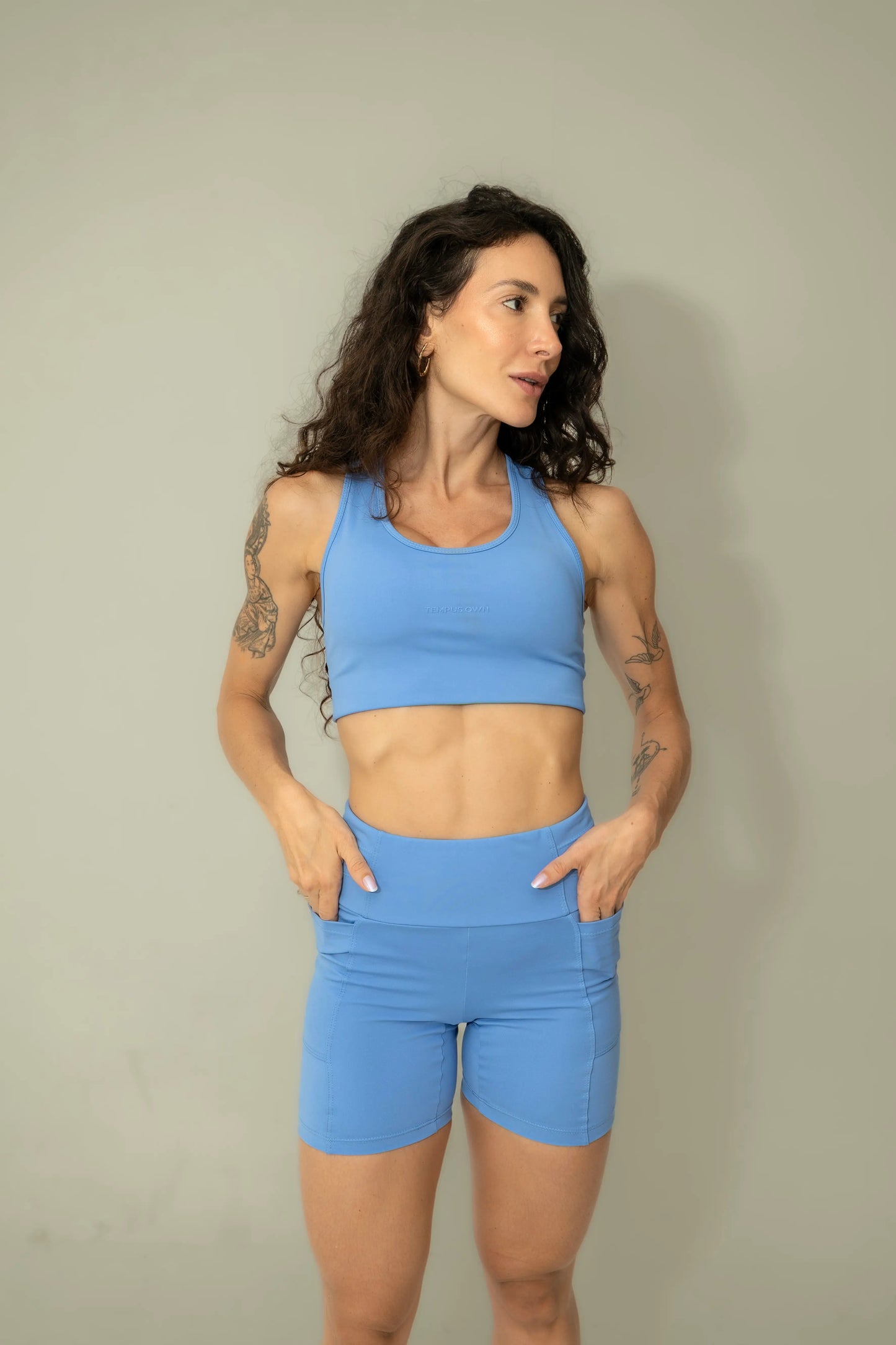 Front view of Caravela Blue high-waisted running shorts, featuring deep side pockets specifically designed for nutrition, hydration, and phone storage.